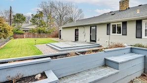 Een woonhuis met voortuin, een houten terras en een schoorsteen.