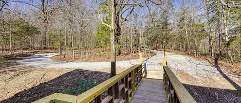 A wooden boardwalk leading through a forested area with a dirt path beside it.