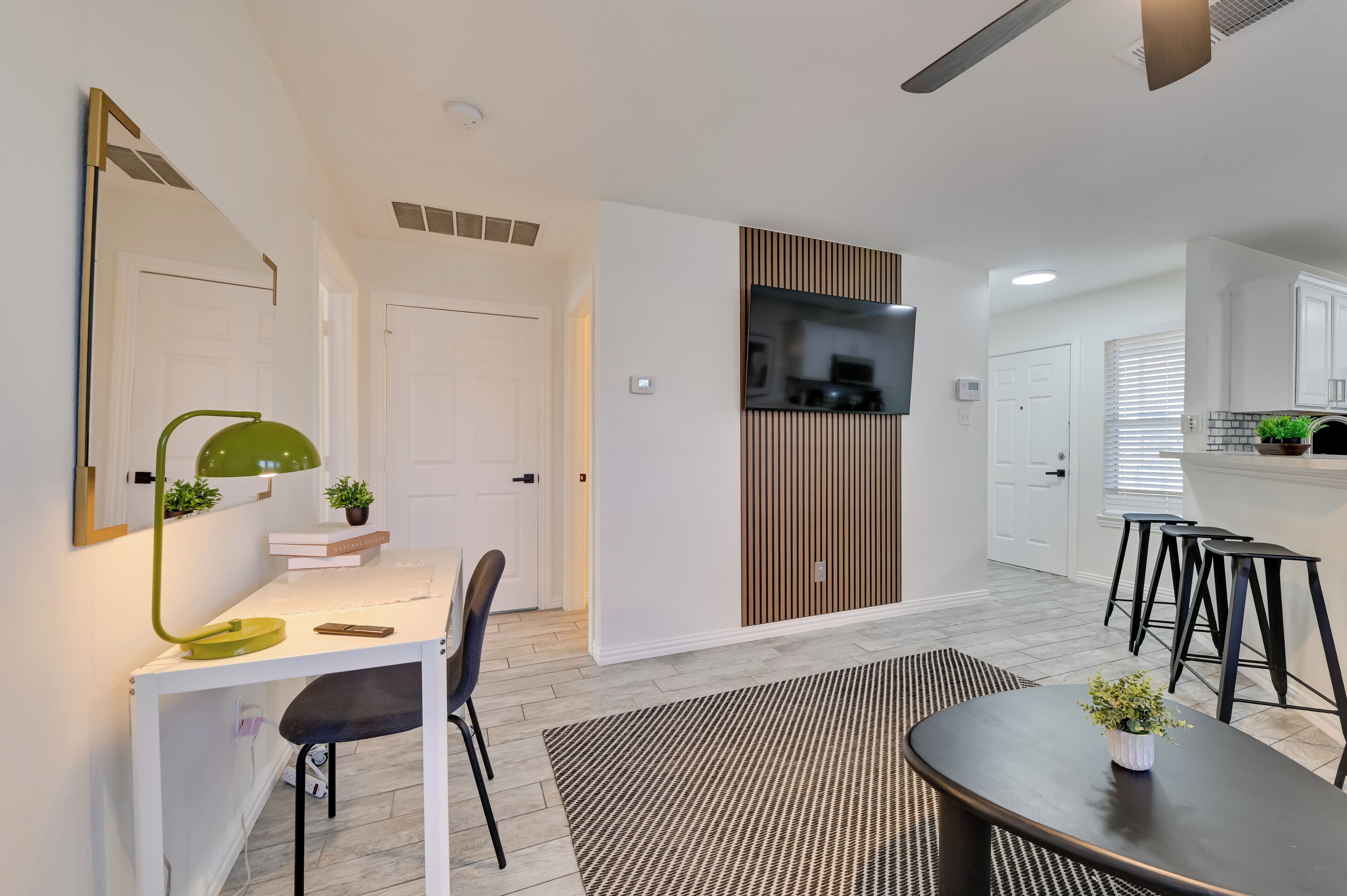 A modern kitchen with white cabinets, a black countertop, and a built-in TV.
