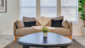 Un salon avec un canapé beige, une table basse ronde et une plante en pot.