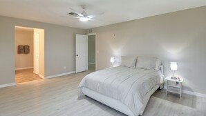A bedroom with a bed, a nightstand, a ceiling fan, and a door leading to another room. - Lehigh Peace Retreat Near Ft Myers! Pet-friendly (Lehigh Acres)