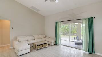 Amplia sala de estar con sofá modular, una mesa de centro y un ventanal corredizo que da a un espacio exterior.