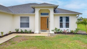 A single-story house with a front porch, a wooden door, and a small front yard. - Lehigh Peace Retreat Near Ft Myers! Pet-friendly (Lehigh Acres)