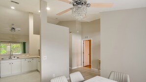 A modern kitchen with white cabinets, a marble countertop, and a dining area with a white table and chairs. - Lehigh Peace Retreat Near Ft Myers! Pet-friendly (Lehigh Acres)