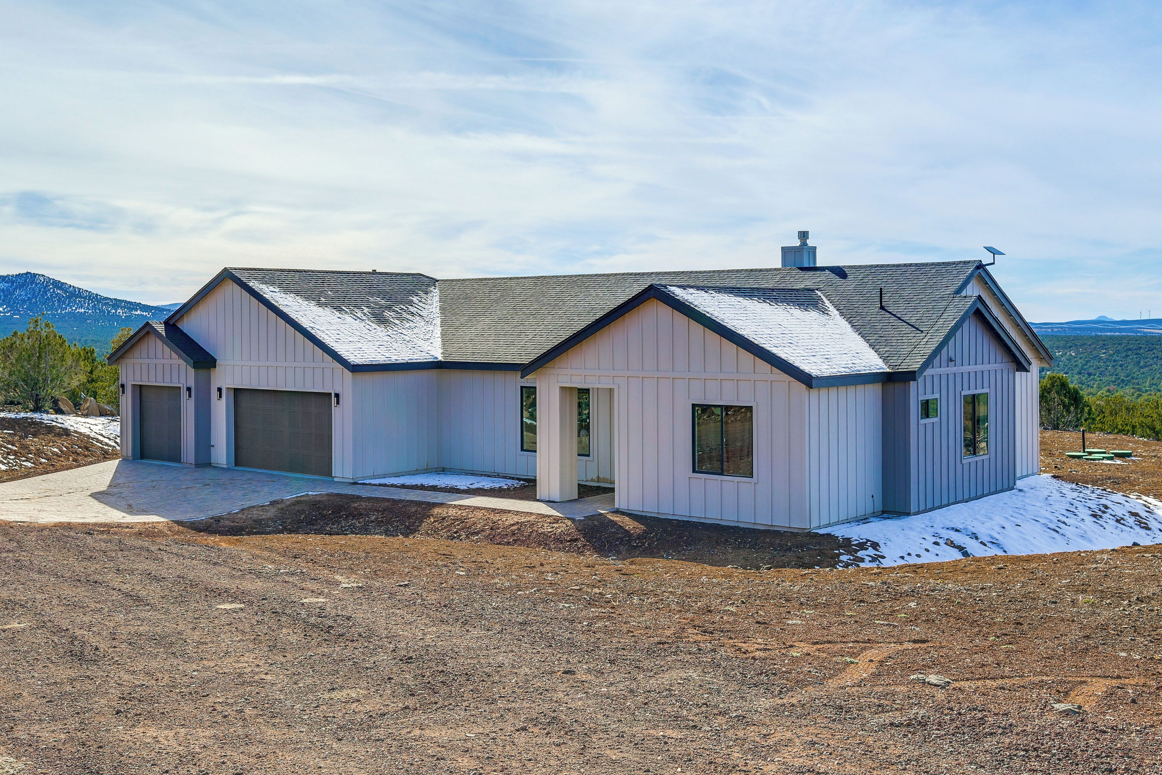 A modern two-story house with a garage, a covered porch, and a view of mountains.