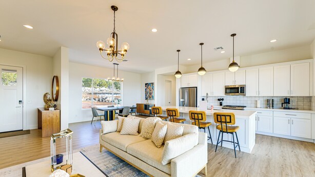 A modern kitchen with white cabinets, stainless steel appliances, and a dining area with wooden chairs. - Gateway to Route 66 Fun! Mtn-view Williams Home (Williams)