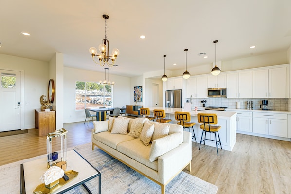A modern kitchen with white cabinets, stainless steel appliances, and a dining area with wooden chairs.