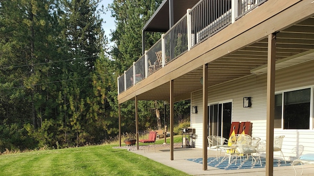 A two-story house with a covered patio, outdoor seating, and a lawn. - 2 Mi to Lake Coeur Dalene! Serene Retreat, Patio (Coeur d'Alene)