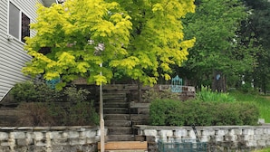 A stone wall, a wooden bench, and a green cart in a garden area. - 2 Mi to Lake Coeur Dalene! Serene Retreat, Patio (Coeur d'Alene)