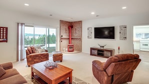 A spacious living room with a fireplace, leather sofas, a wooden coffee table, and a large TV. - 2 Mi to Lake Coeur Dalene! Serene Retreat, Patio (Coeur d'Alene)