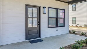 A building with a front door, two windows, a small porch, and a metal vent.
