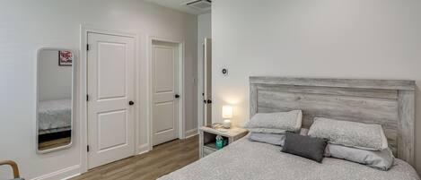 Quarto com cama, mesa de cabeceira, luminária e ventilador de teto.