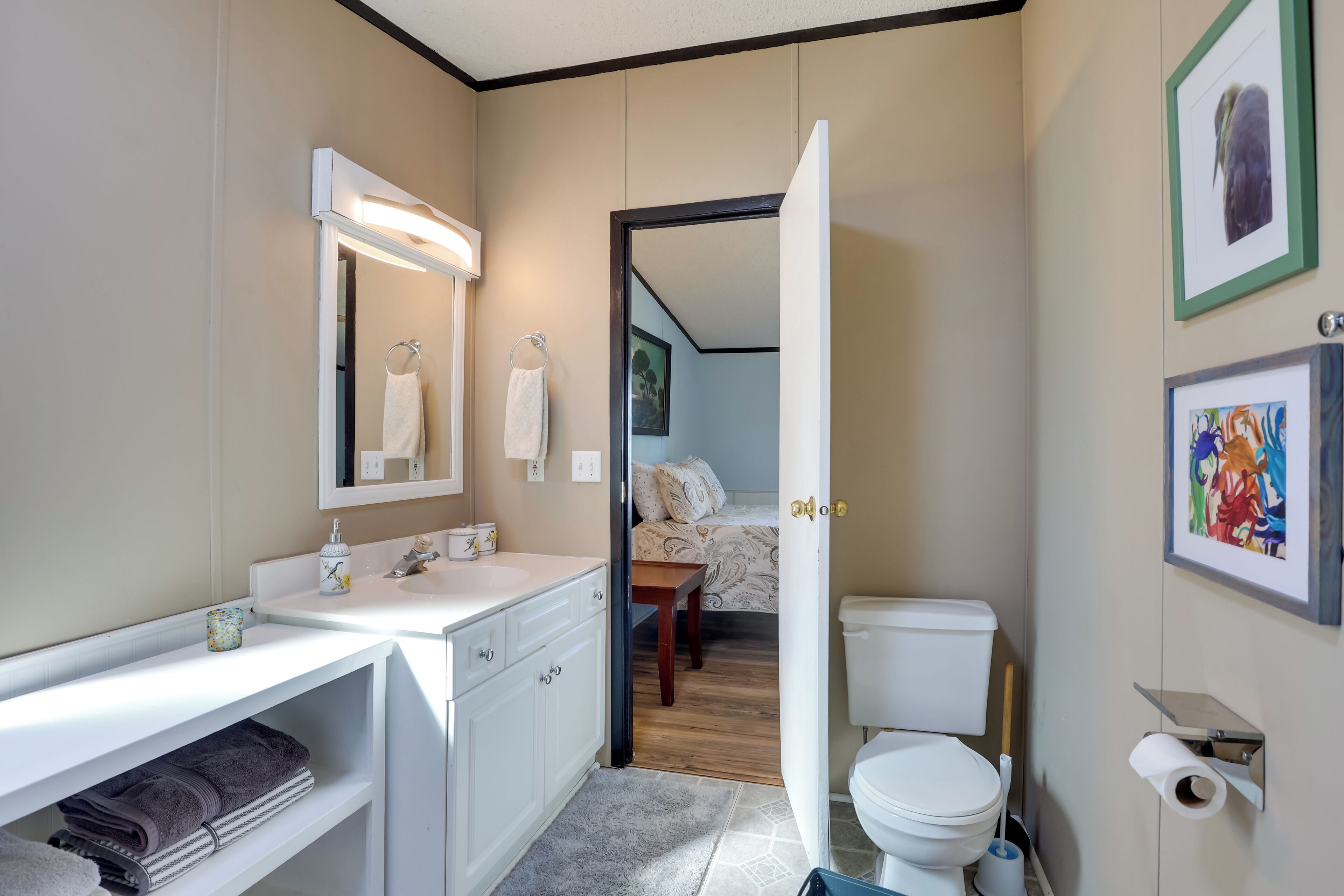 A modern bathroom with a white vanity, a mirror, a toilet, and a shower area.