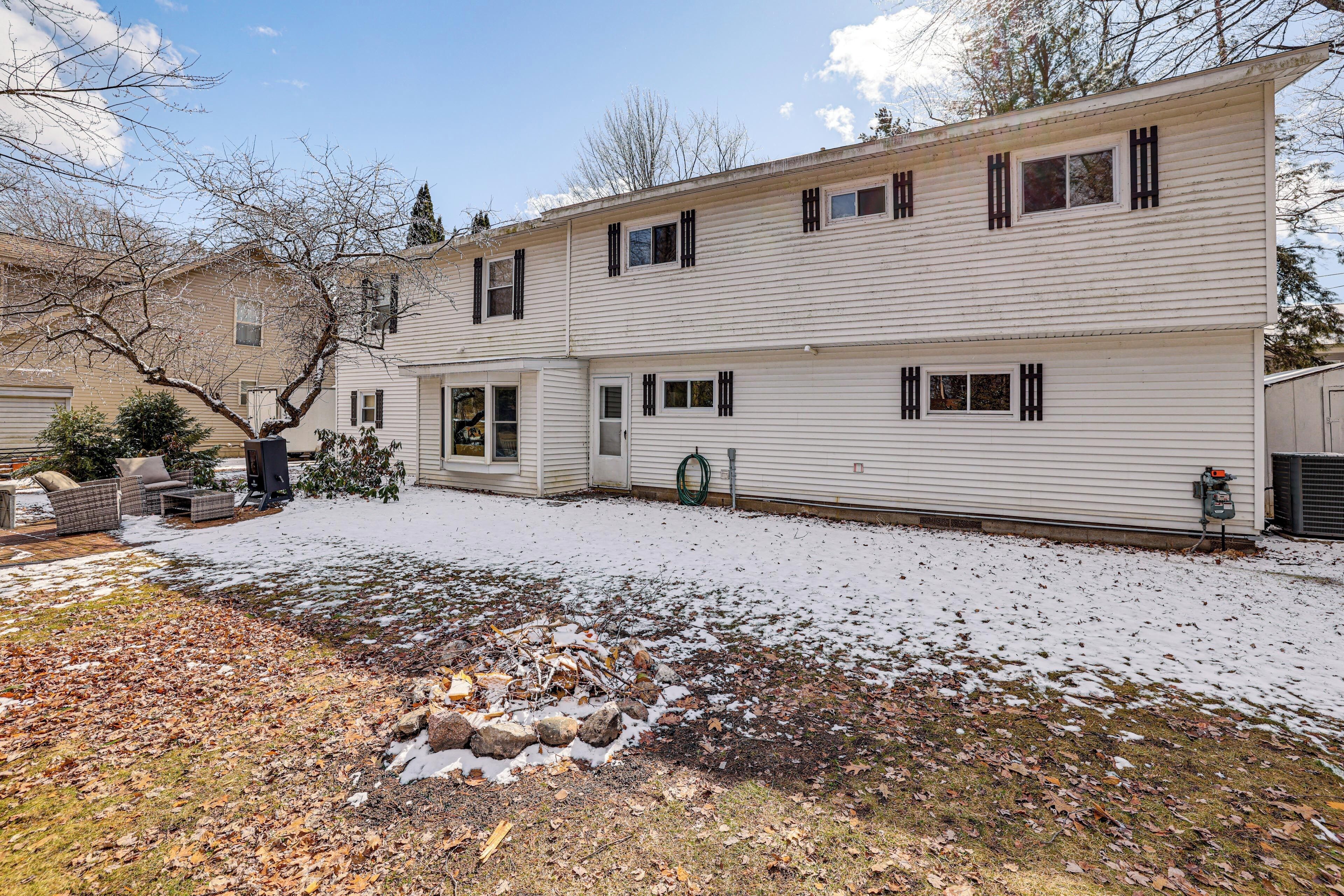 A two-story house with a covered patio, a visible garage door, and a snow-covered yard.