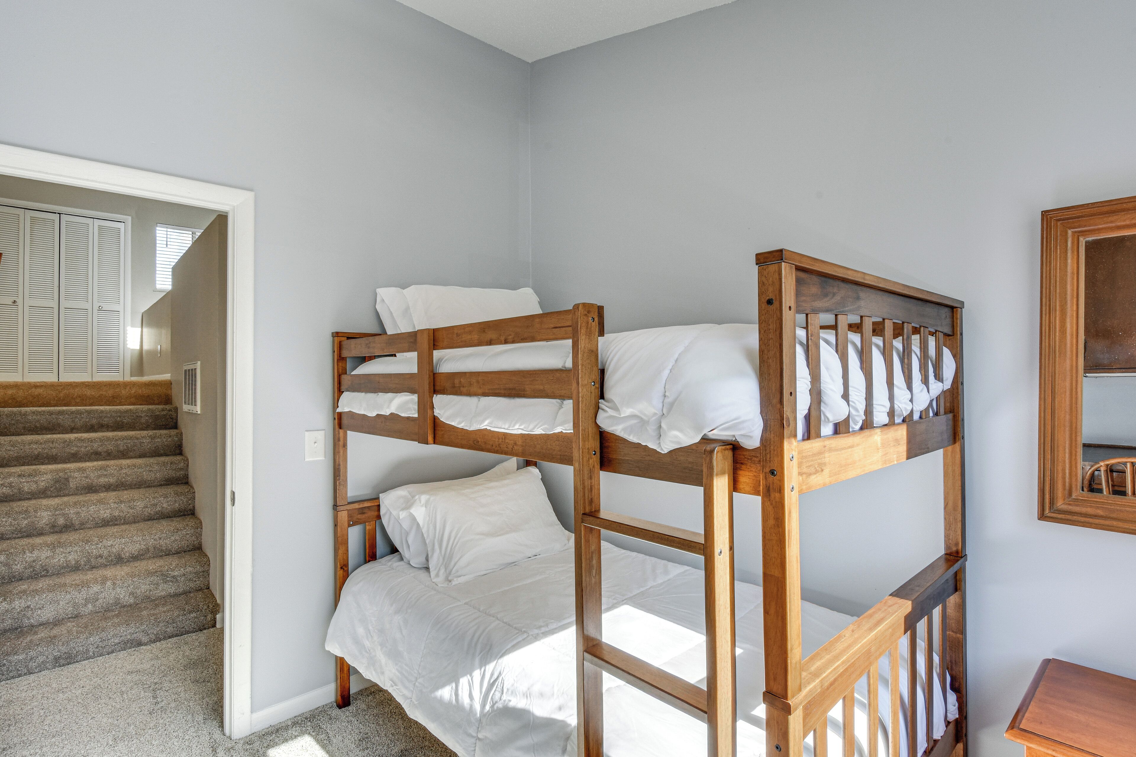 Une chambre avec un lit superposé, un escalier et une petite table.