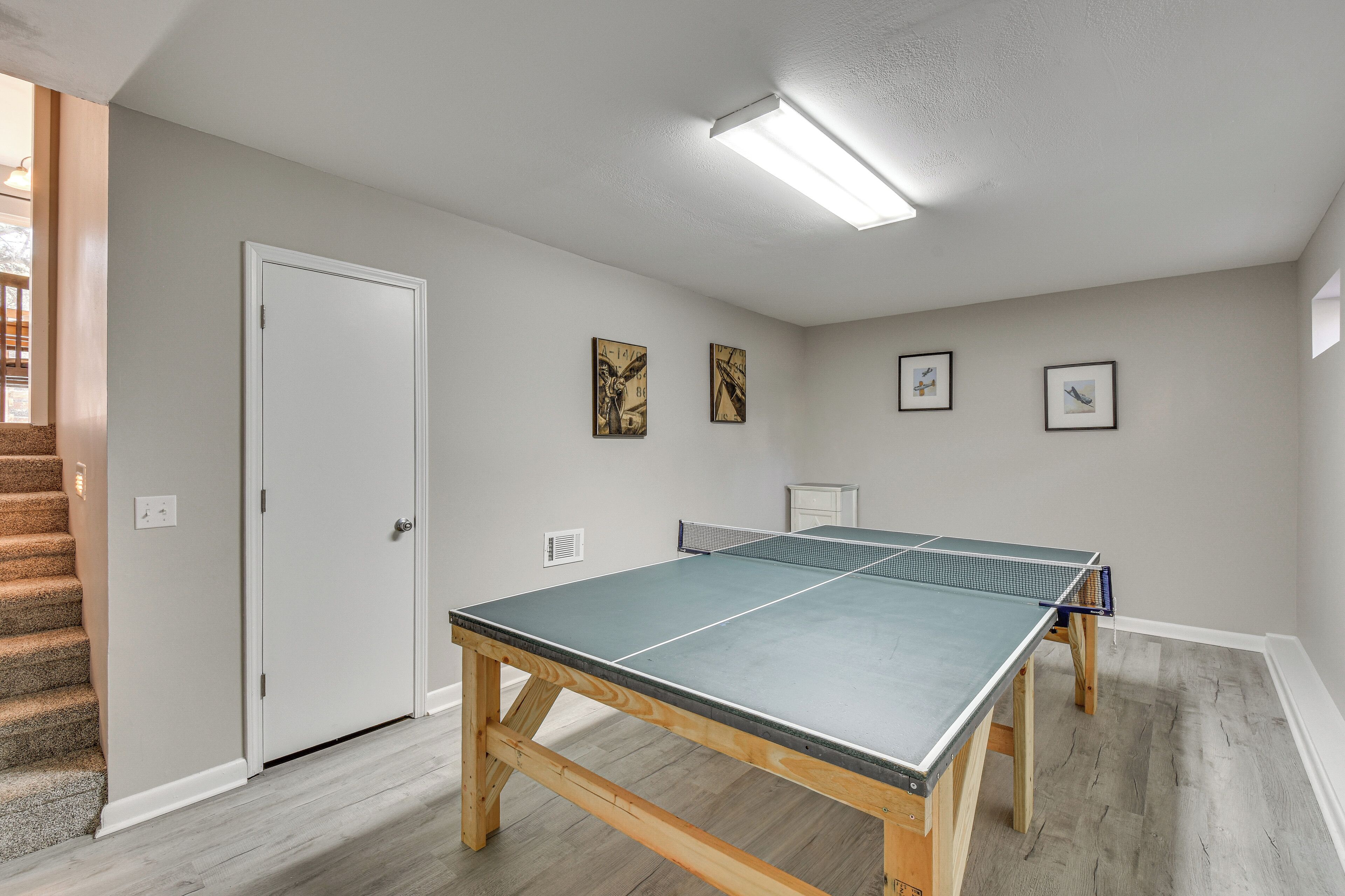 A room with a ping pong table, a door, and a staircase.
