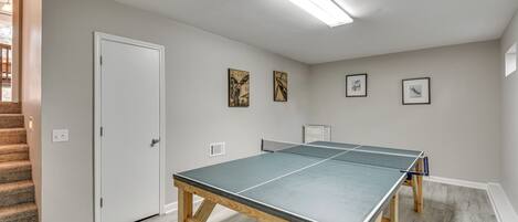 A room with a ping pong table, a door, and a staircase.
