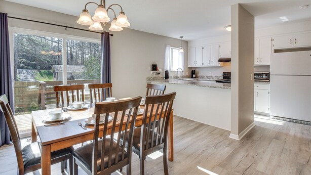 Una cocina moderna con armarios de madera, un comedor con mesa y sillas, y vistas al exterior.