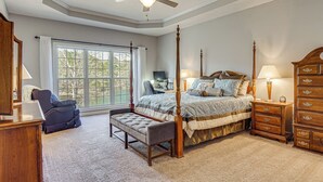 Een slaapkamer met een hemelbed, een bureau, een stoel, een kast en een plafondventilator.