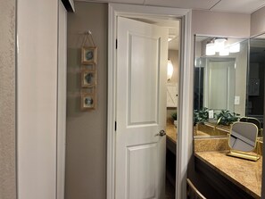 A hallway with a white door, a mirror with a gold frame, and a wall-mounted picture frame. - Rent Ready Beautiful Unit in Caravelle in Myrtle Beach! (Myrtle Beach)