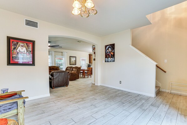 A spacious living area with a staircase, a dining area, and a kitchen in the background.