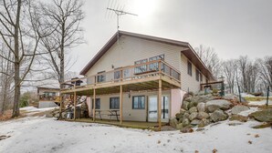 A two-story house with a balcony, a covered patio, and a stone retaining wall. - Fishing Paradise: Lakefront Duplex in Northwoods (Pearson)