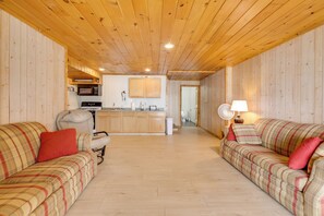 A wooden interior with two couches, a kitchen, and a fan. - Fishing Paradise: Lakefront Duplex in Northwoods (Pearson)