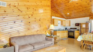 Un intérieur en bois comprenant un canapé, une table, une lampe et un coin cuisine avec des placards et des appareils électroménagers.