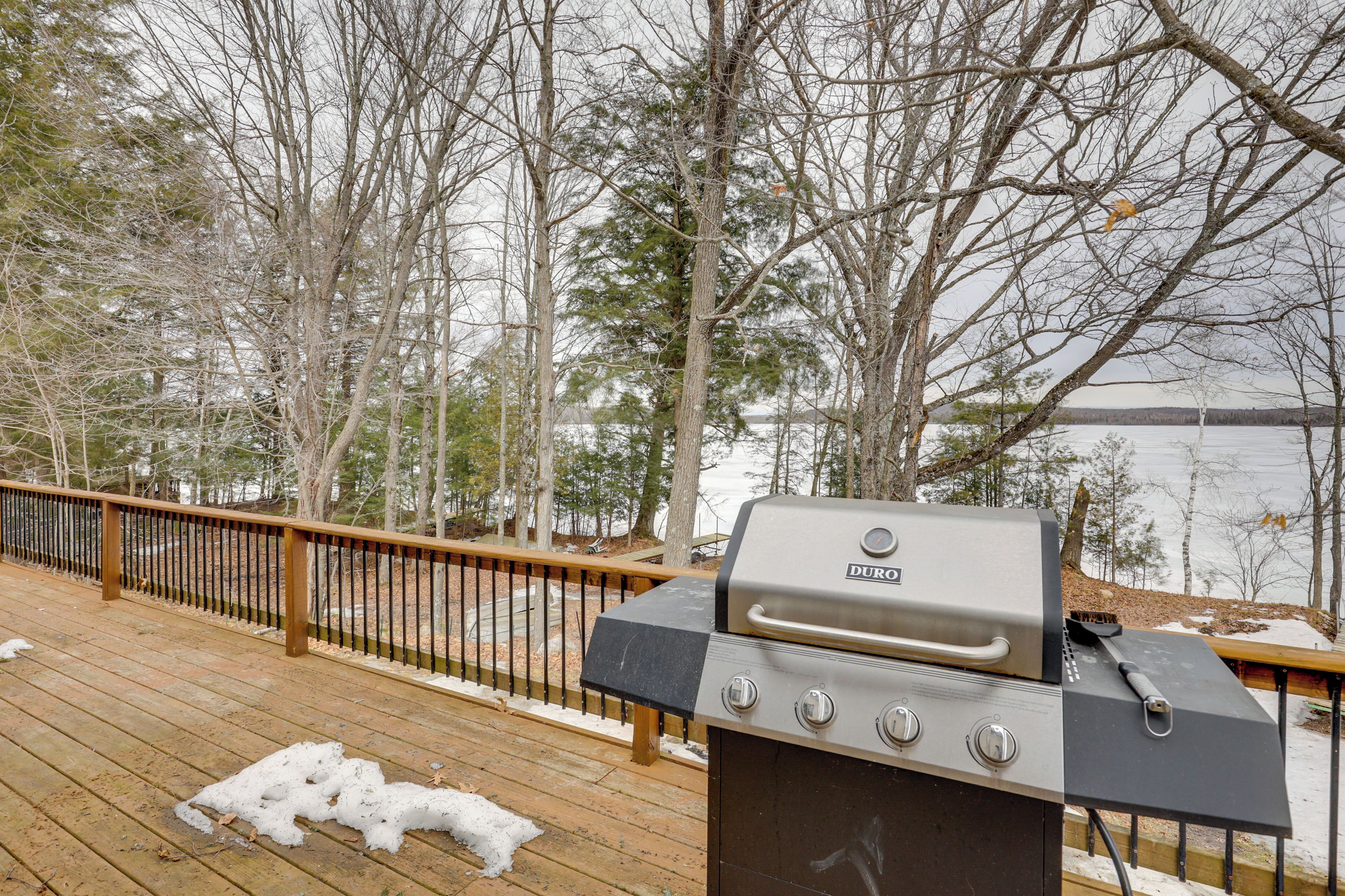 A wooden deck with a grill and a view of a lake.