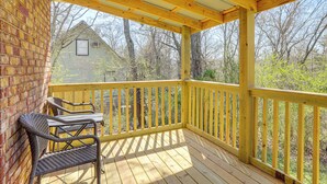 Une terrasse en bois avec une rambarde, deux chaises en osier et une table.