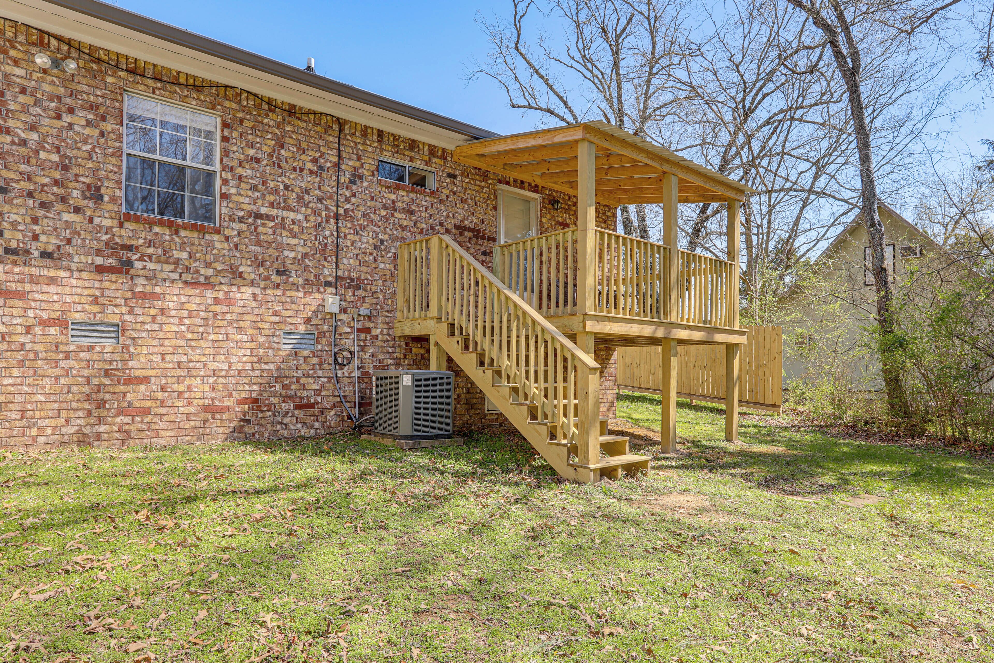 A brick house with a wooden deck and a staircase leading to a covered porch.
