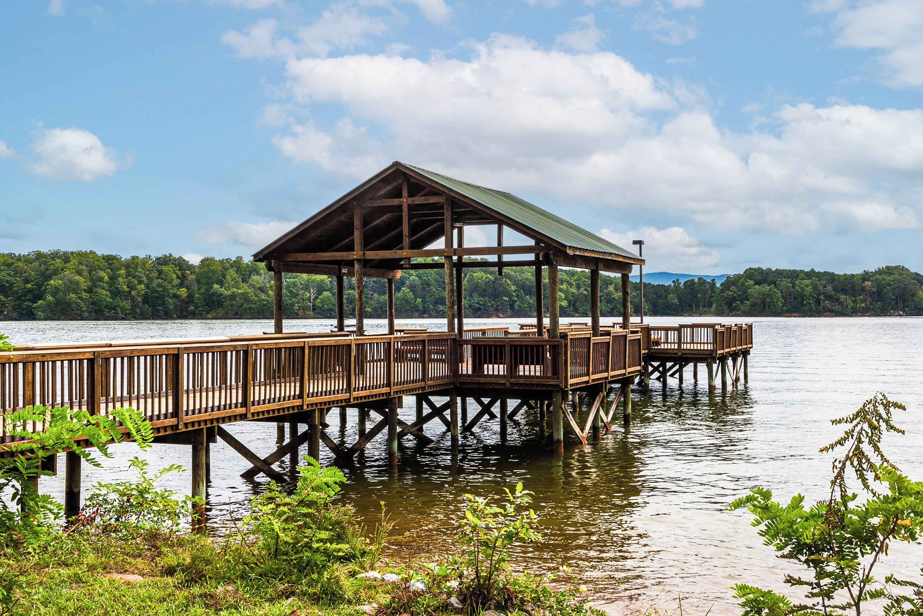 A wooden pier extending into a lake with a covered pavilion at the end.