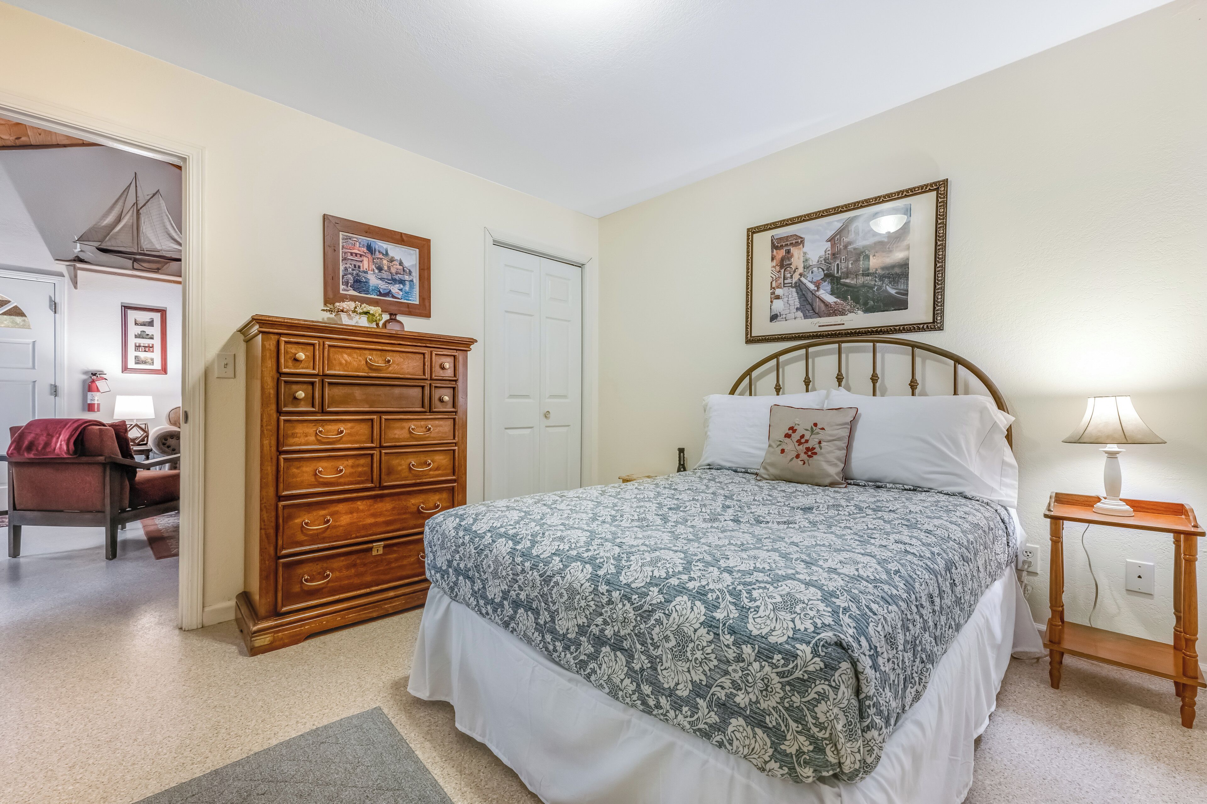 A bedroom with a bed, dresser, and two framed pictures on the wall.