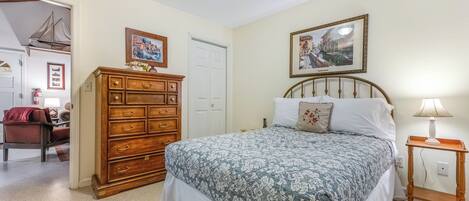 A bedroom with a bed, dresser, and two framed pictures on the wall.