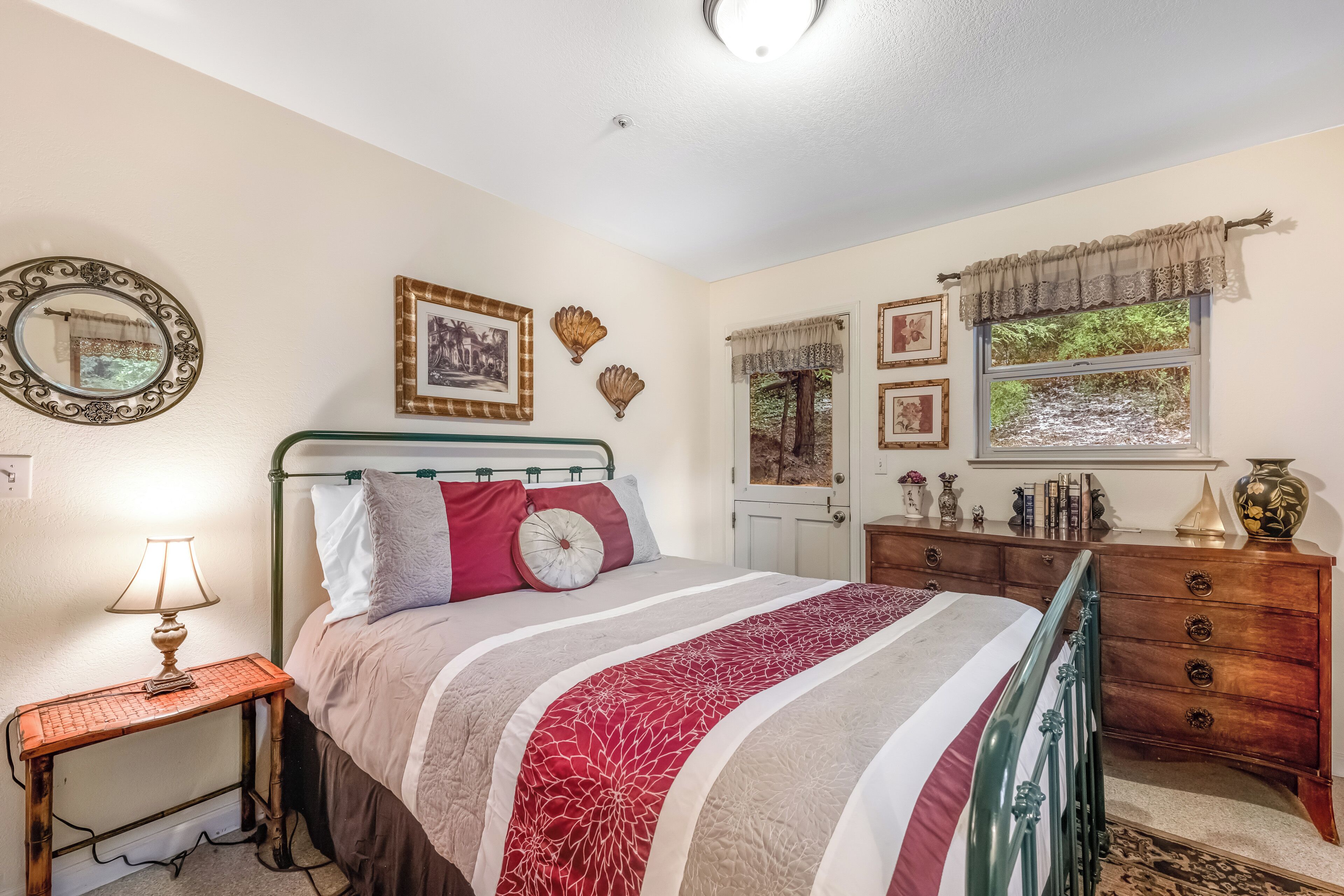 Une chambre à coucher comprenant un lit, une table de chevet, une commode et une fenêtre avec des rideaux.