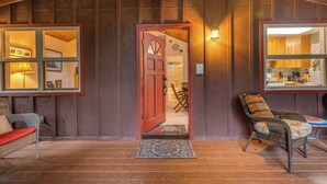 A wooden interior with a red door, wicker furniture, and a visible kitchen area. - Rustic Mtn-view Home w/ Wood Stove: Dog Friendly (Felton)