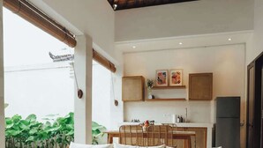 Een moderne woonkamer met een glazen tafel, een bank met kussens, een plafondventilator en uitzicht op een zwembad.