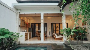 Een modern huis met een zwembad, een eethoek en een woonkamer.