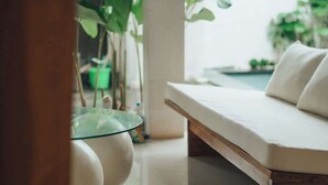 Een modern interieur met een glazen tafel, een witte bank en groene planten.