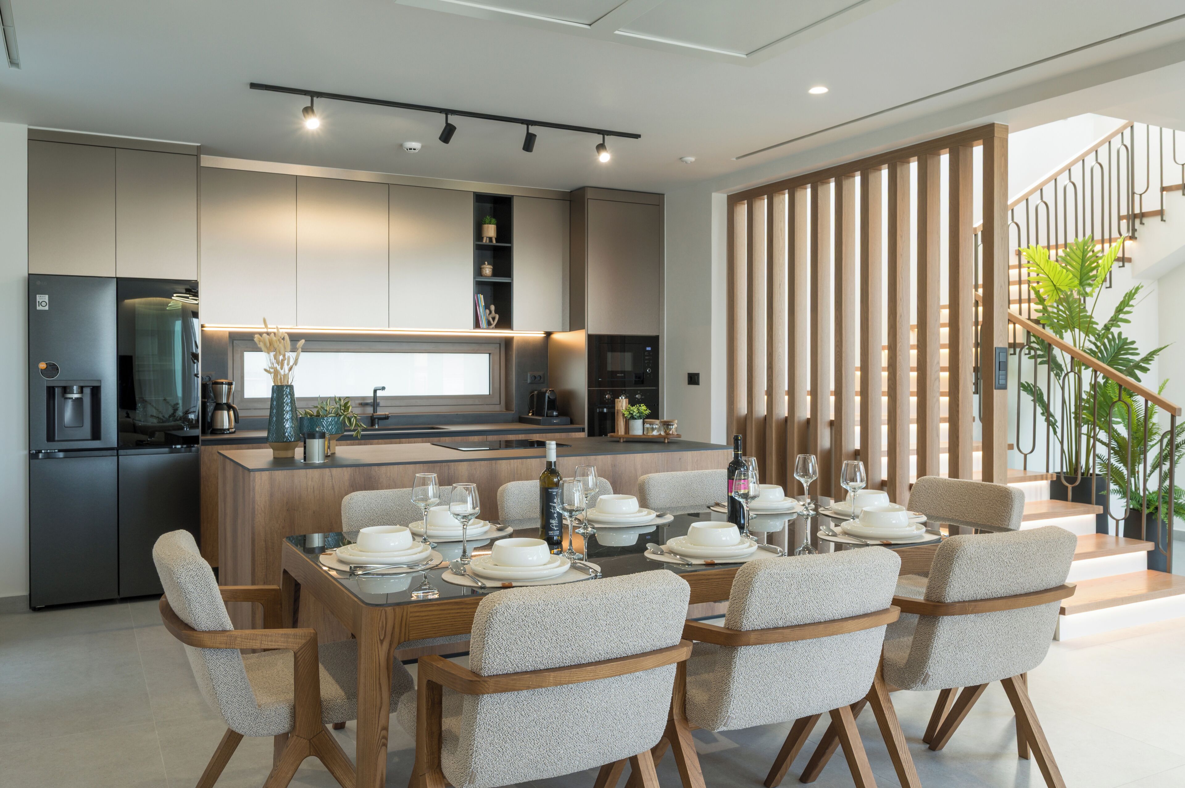 A modern kitchen with a dining area, built-in appliances, and a staircase with a railing.