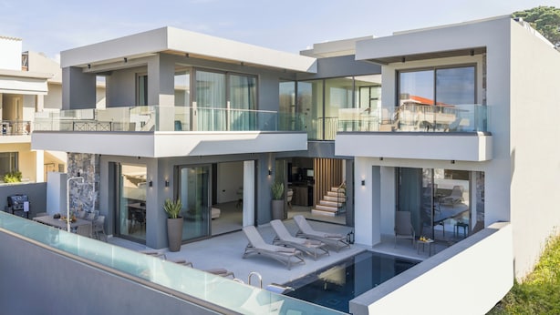 Une maison moderne à deux étages dotée d’une piscine, d’un espace salon extérieur et d’un balcon.