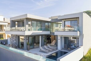 A modern two-story house with a swimming pool, outdoor seating, and a balcony. - Villa Armonia Blue (Agia Marina)
