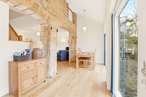 Amplia habitación con un arco de piedra, muebles de madera y un área de comedor con vistas a través de un gran ventanal.