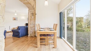 A dining area with a wooden table set for four, a blue sofa, and a stone wall.