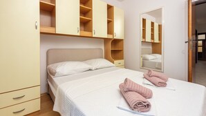 Een slaapkamer met een bed, een kledingkast, een spiegel en een deur naar de badkamer.