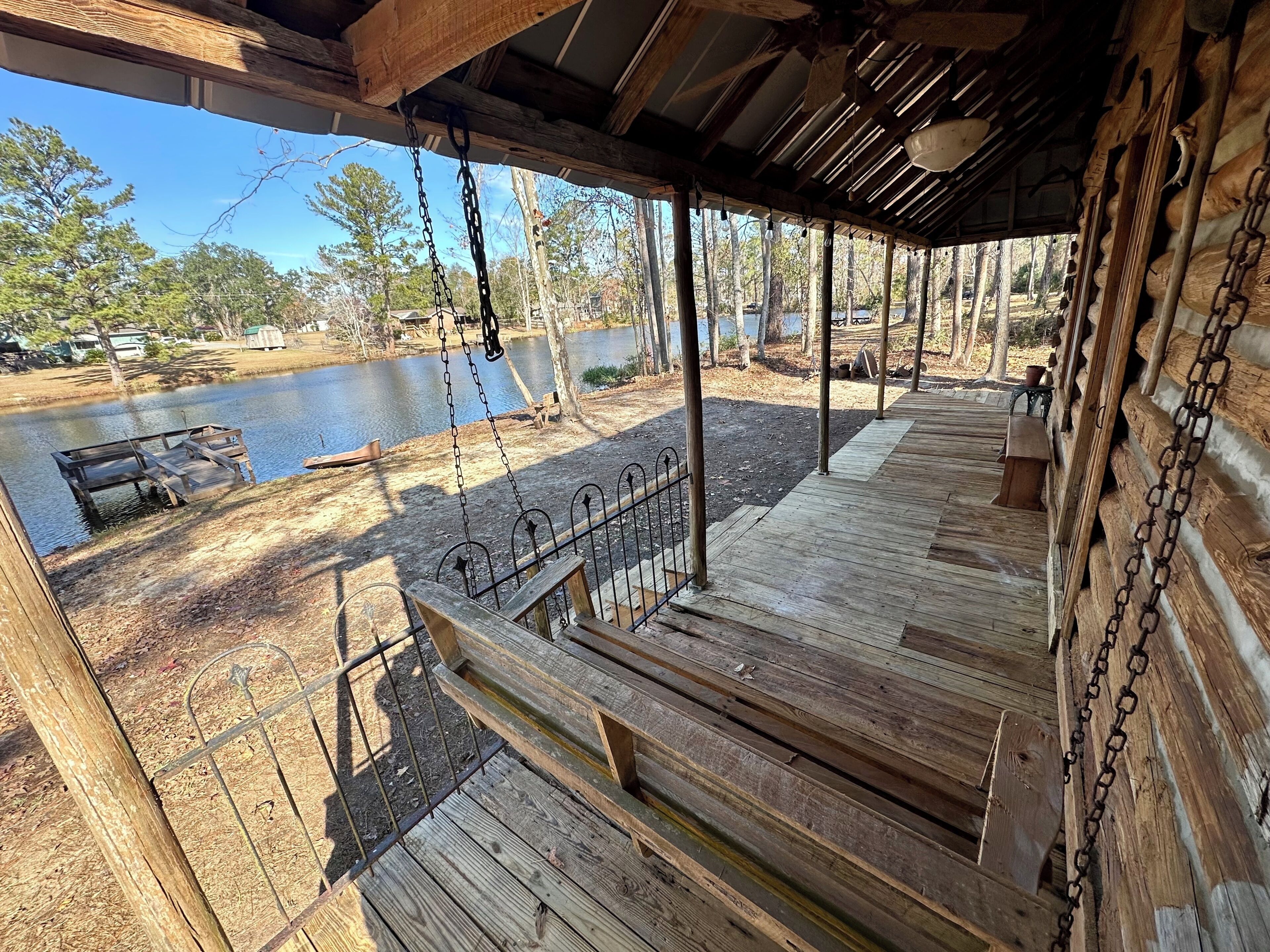 A wooden deck with a swing set overlooking a lake.