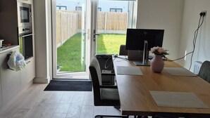 A modern kitchen with built-in appliances, a dining area with a table and chairs, and a large sliding glass door leading to a backyard. - Room-cozy & Peaceful Retreat Near Dublin (Cappagh)