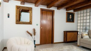 A room with a wooden ceiling, a door, a mirror, a sofa, a patterned rug, and a decorative cabinet. - Apartament 3 (Timișoara)