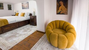 A bedroom with a bed, nightstand, lamp, and a round yellow chair. - Apartament 3 (Timișoara)