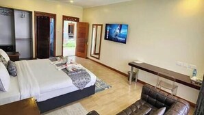 Une chambre d’hôtel avec un lit, un canapé en cuir, une télévision et un bureau.